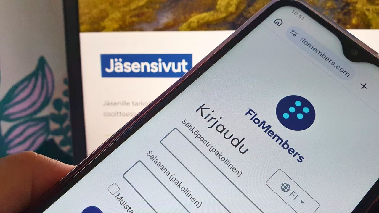 Puhelin, jossa FloMembers kirjautumissvu ja taustalla tietokoneen näyttö, jossa auki BMOL ry:n jäsensivu